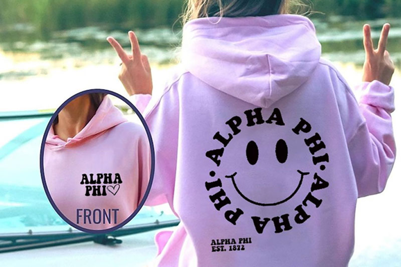 A girl wearing a pink hoodie with a logo of Alpha PHI